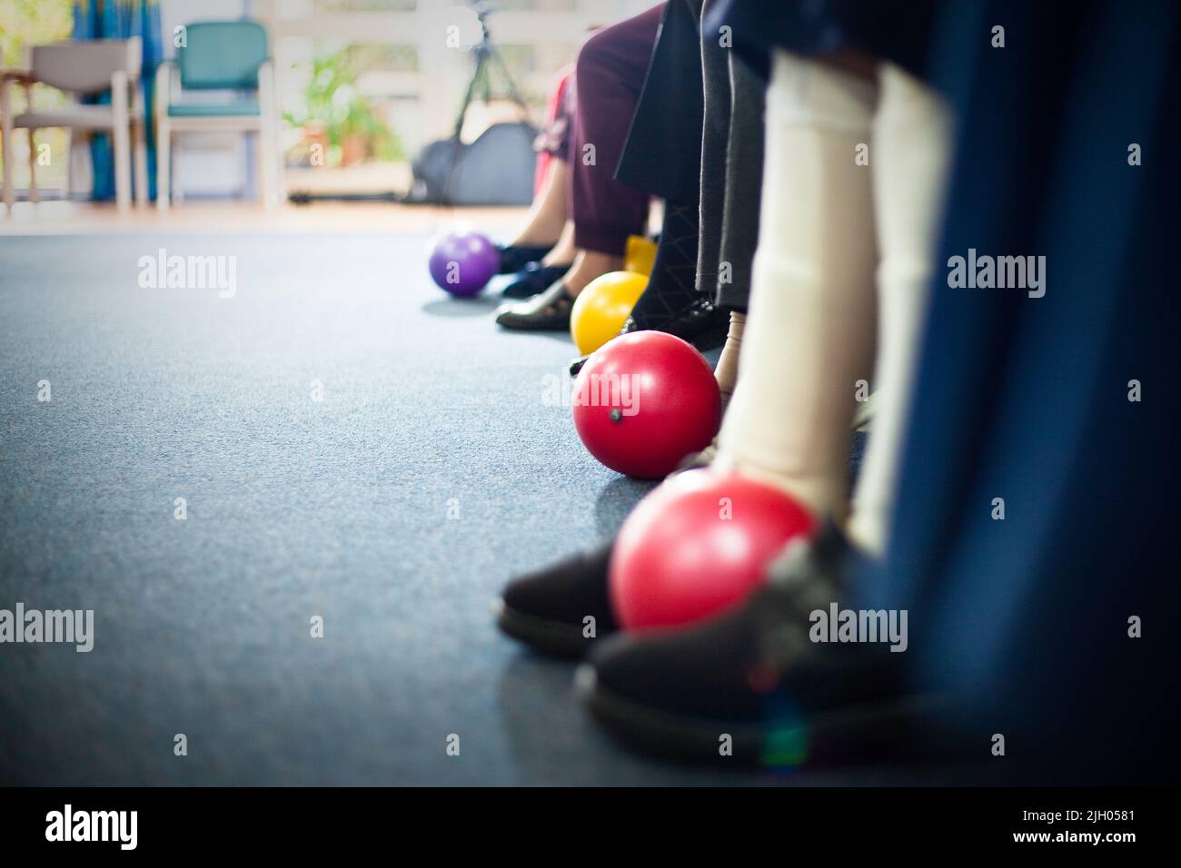 NAHAUFNAHME DER FÜSSE ÄLTERER BEWOHNERINNEN UND BEWOHNER, DIE BEINÜBUNGEN MIT BÄLLEN IN EINEM ALTERSHEIM IN AUSTRALIEN DURCHFÜHREN. Stockfoto