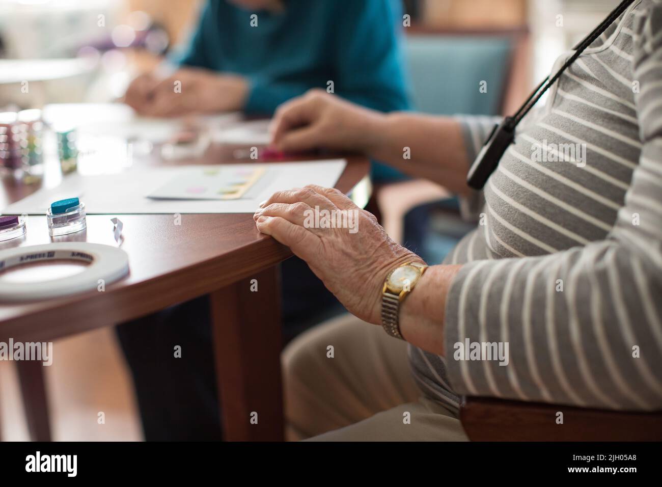 NAHAUFNAHME EINER ÄLTEREN DAME IN EINEM ALTENHEIM, DIE KARTEN ERSTELLT Stockfoto