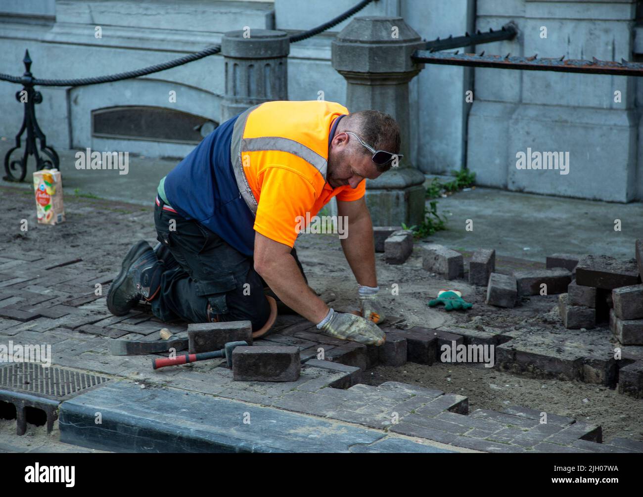 Arbeiter, der Pflastersteine in einer Amsterdamer Straße repariert Stockfoto