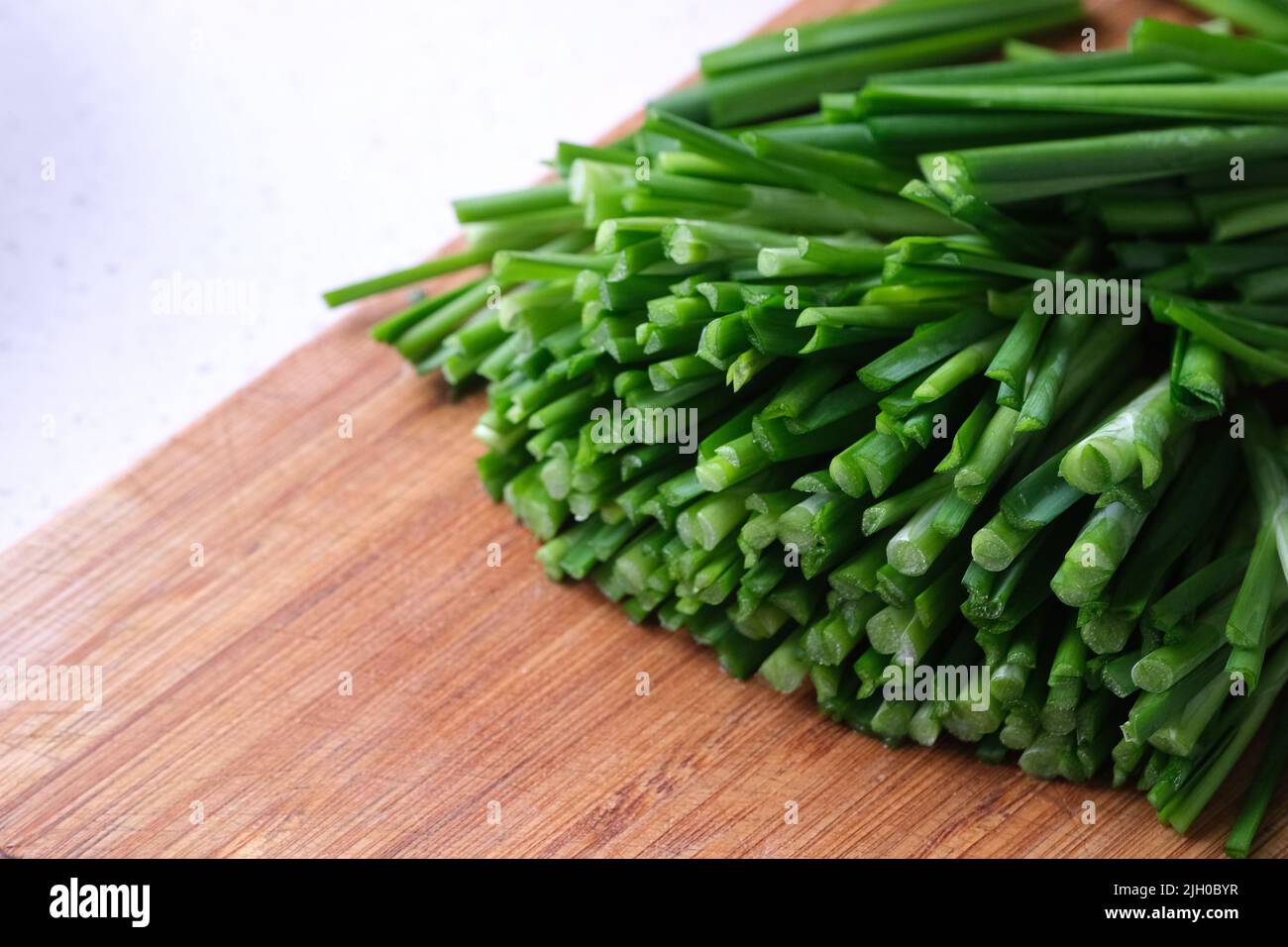 Gehackter grüner Knoblauch-Schnittlauch (chinesischer Schnittlauch) auf Holzschneidebrett Stockfoto