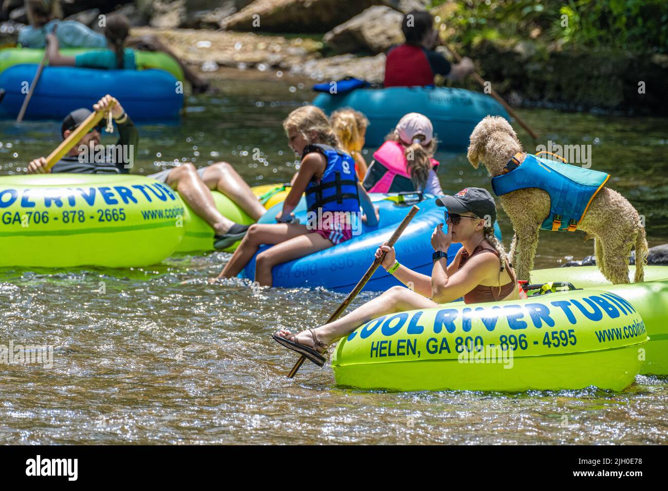 Familien tummeln sich auf dem Chattahoochee River, zusammen mit einem lebensjackigen Labradoodle, in Helen, einer alpinen Touristenstadt in den Nord-Georgia-Bergen. Stockfoto