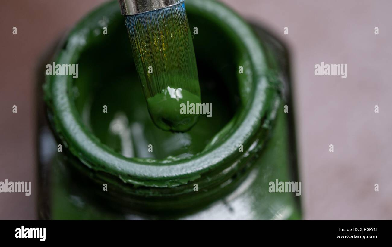 Acryl dunkelgrüne Farbflasche und Pinsel Nahaufnahme hellen Hintergrund Stockfoto