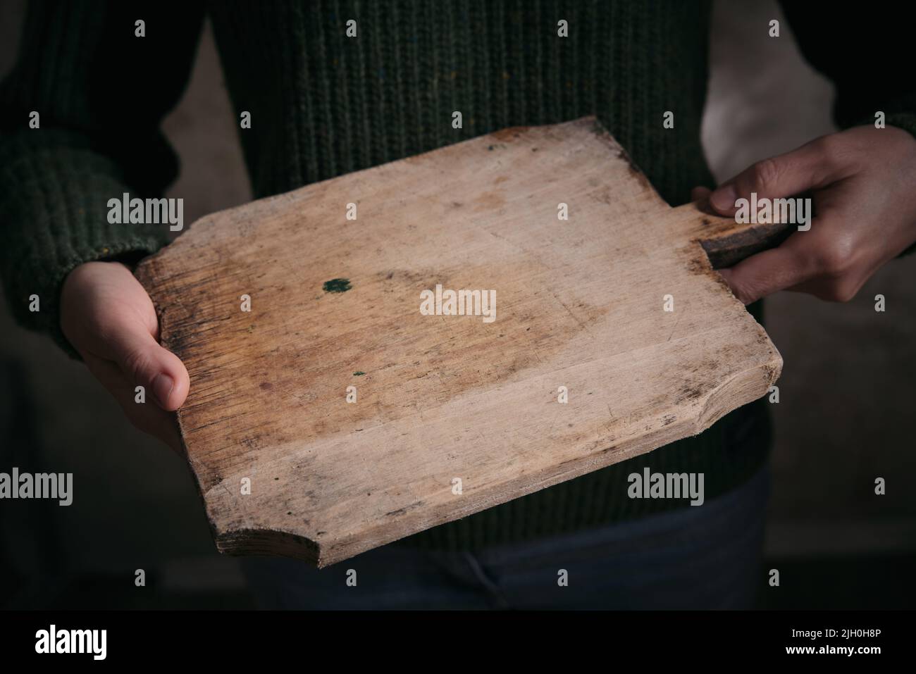 Hoher Winkel der Ernte anonyme Frau in warmen Pullover mit schäbigen Holz Schneidebrett in den Händen Stockfoto
