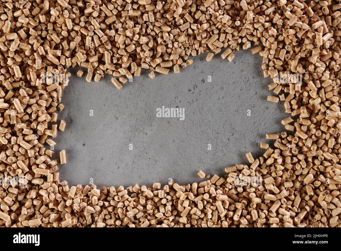 Von oben aus Haufen von Massivholz Biokraftstoff Pellets auf grauem Tisch mit rechteckigem Loch verstreut Stockfoto