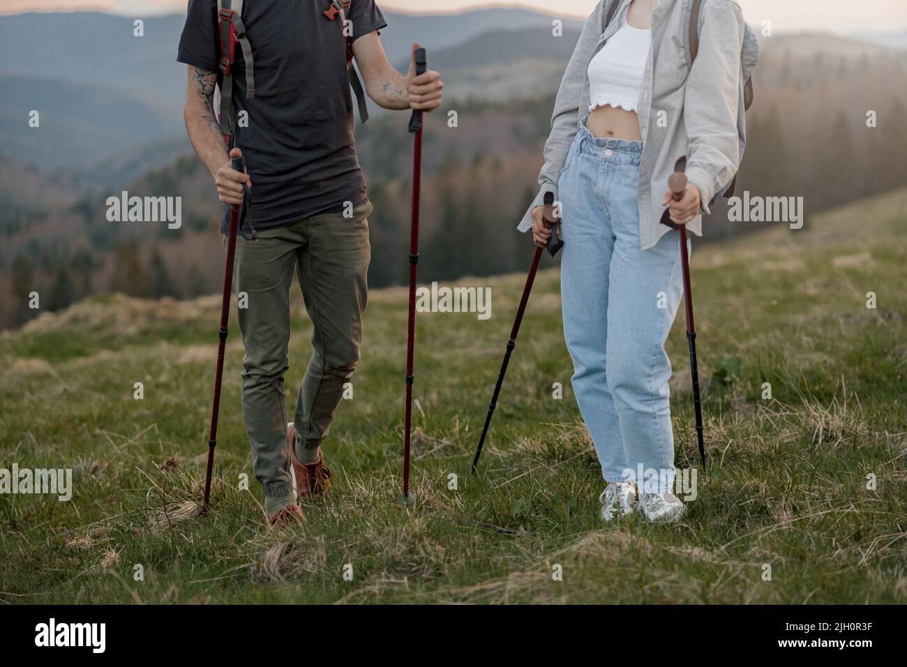 Nahaufnahme von männlichen und weiblichen Beinen in Trekkingschuhen mit Gehstöcken in den Händen. Reisende. Stockfoto