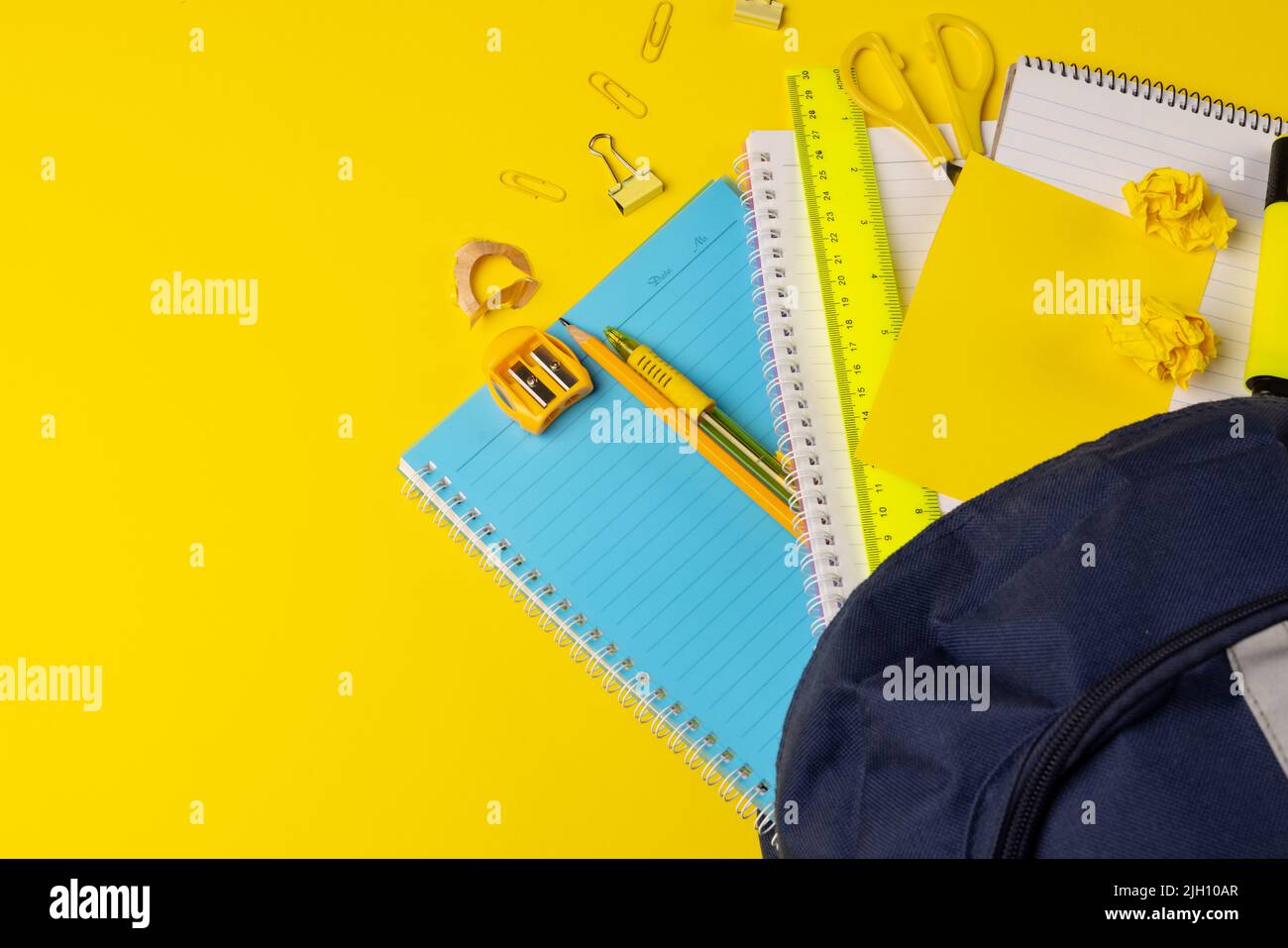 Video der Komposition mit Rucksack und Schulsachen auf gelber Oberfläche Stockfoto
