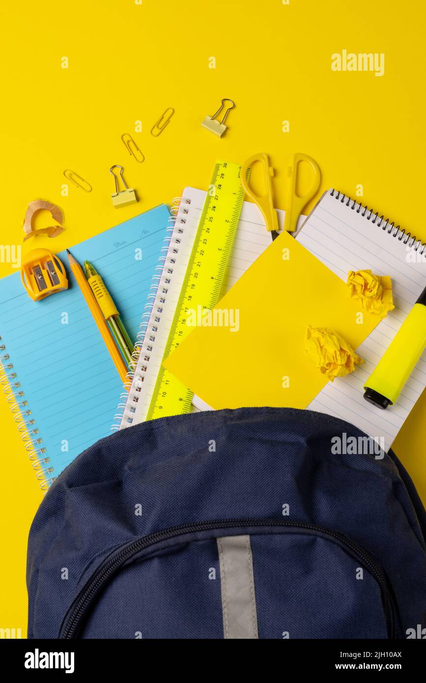 Vertikales Video der Komposition mit Rucksack und Schulsachen auf gelber Oberfläche Stockfoto