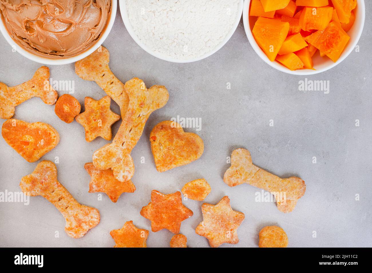 Hausgemachte Bio-Hundekeks und Zutaten Leckereien auf grauer Oberfläche mit Kopierraum Stockfoto