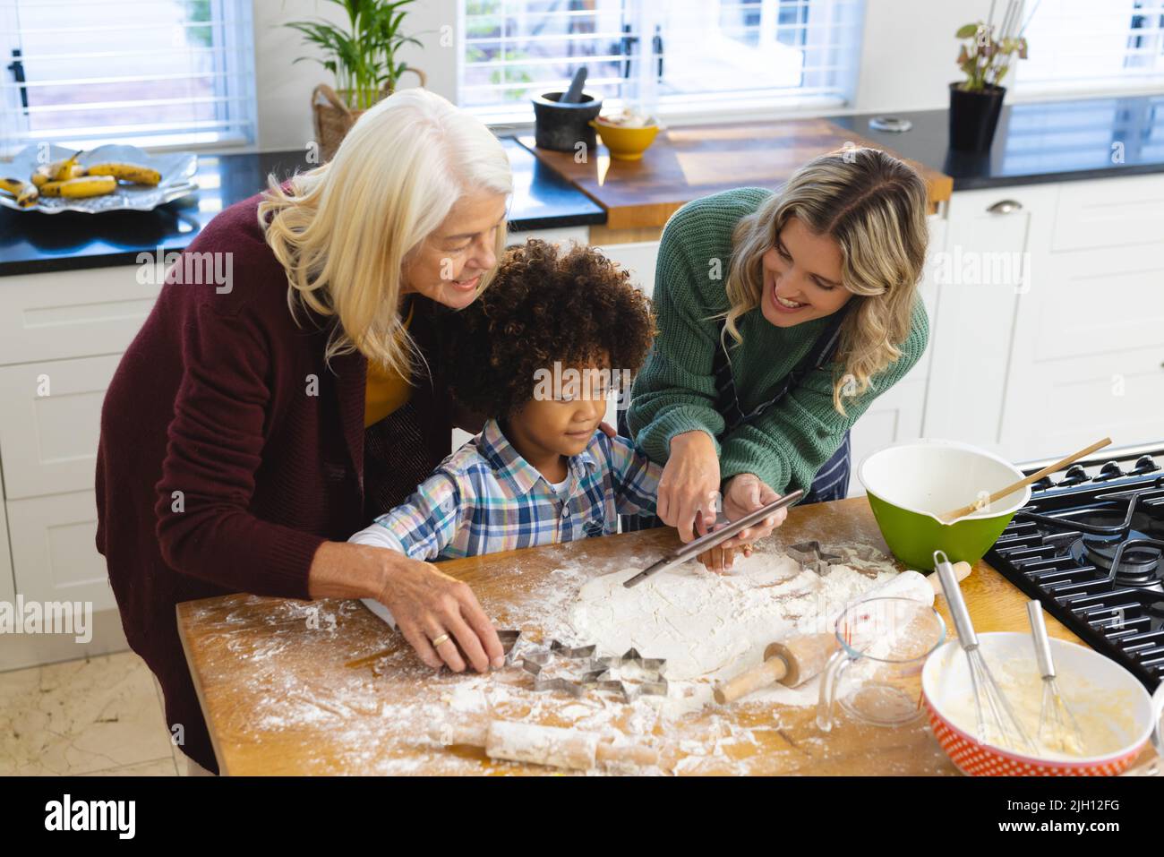 Ein Blick aus der Perspektive einer Familie mit mehreren Rassen, die Lebensmittel zubereitet, während sie sich das Rezept auf dem Tablet ansieht Stockfoto