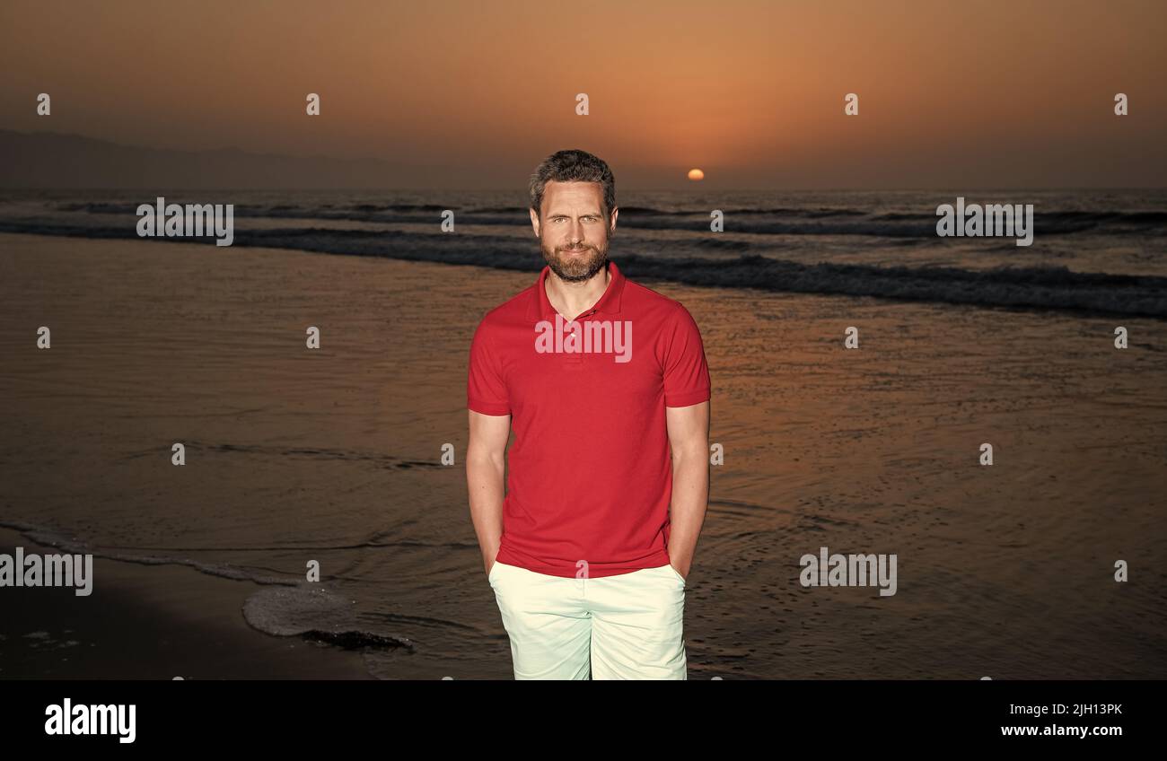 Fröhlicher Mann über dem Meer am sonnigen Sommerstrand, Urlaub Stockfoto