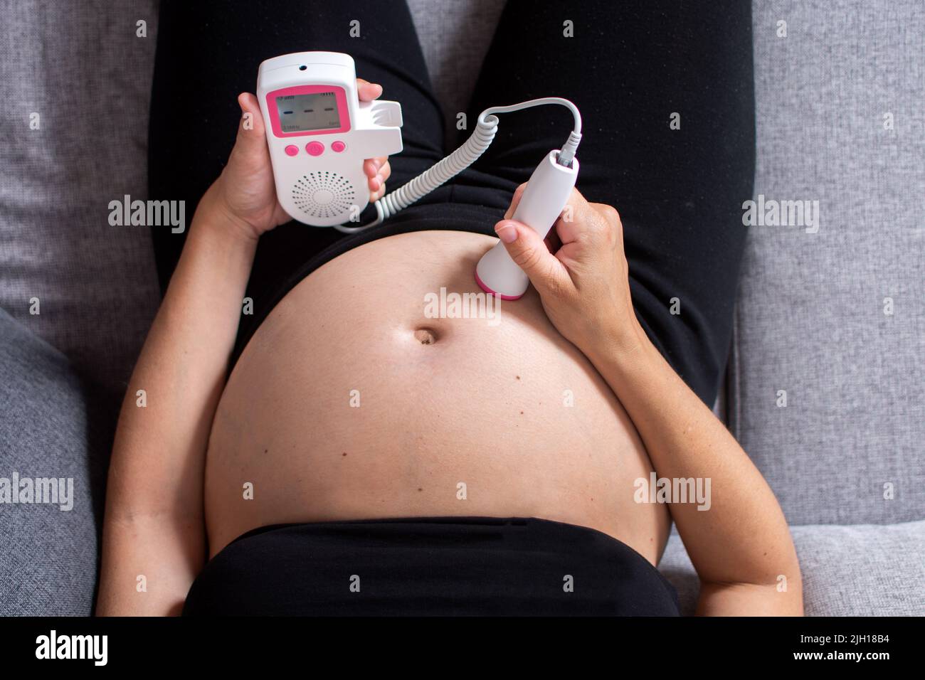 Schwangere Frau mit einem fetal Doppler zu Hause Stockfotografie - Alamy