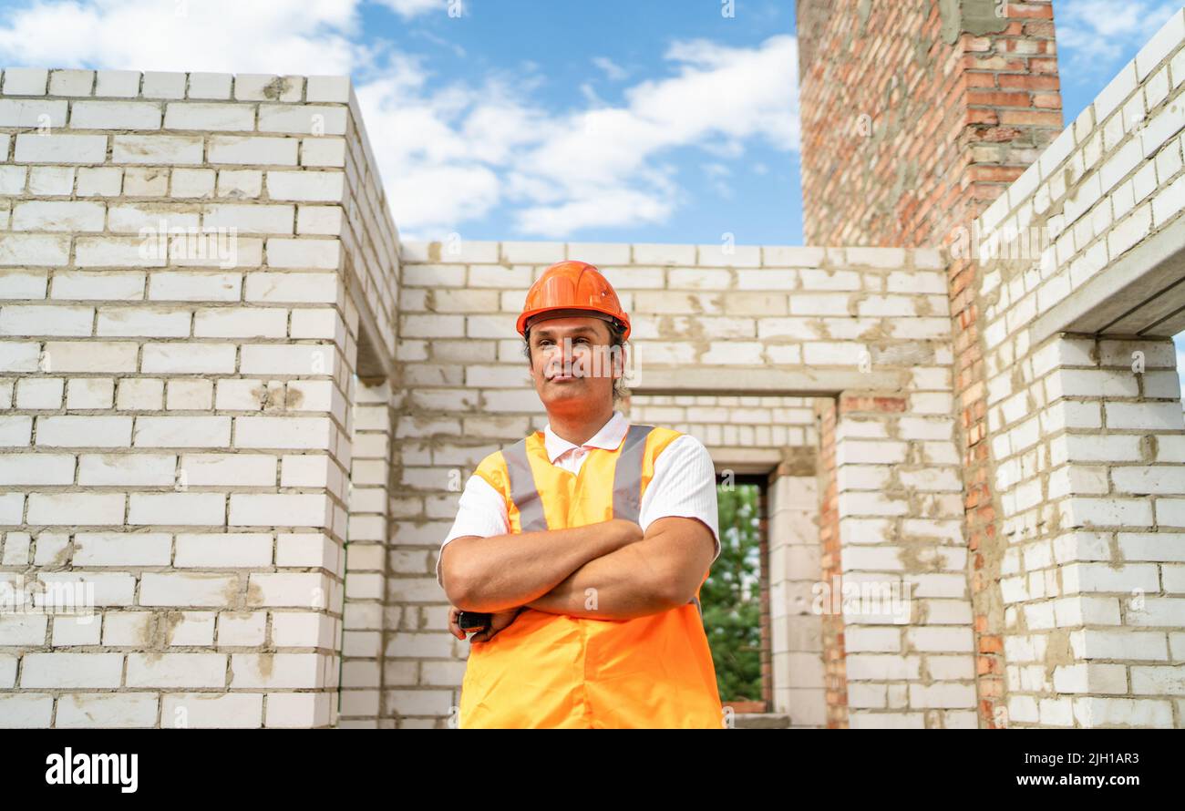 Erfolgreicher Baumeister in Hardhat kontrolliert die Qualität der Arbeit auf der Baustelle. Inspektion und Engineering im Neubau des Hauses. Stockfoto