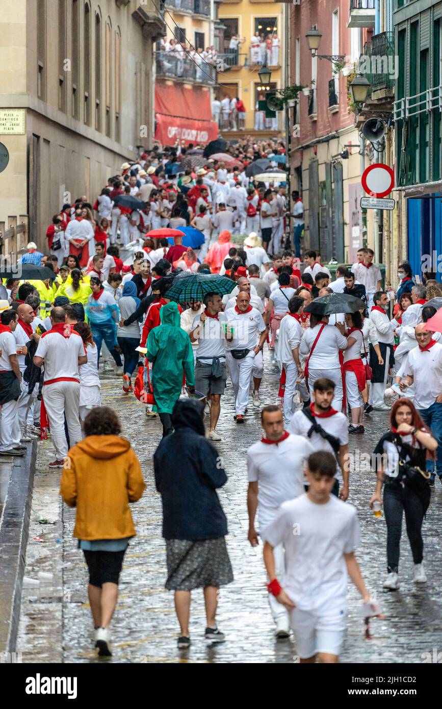 Pamplona, SPANIEN - Juli 06 2022: Straßen von Pamplona am Anfang von San Fermin. Menschen, die in weiß und rot gekleidet sind, gehen zum Rathausplatz. Stockfoto