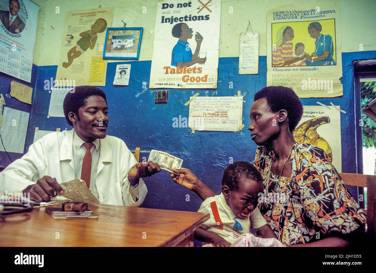 Uganda, Mutter mit Kind, die den Arzt besucht und Geld bezahlt. Stockfoto