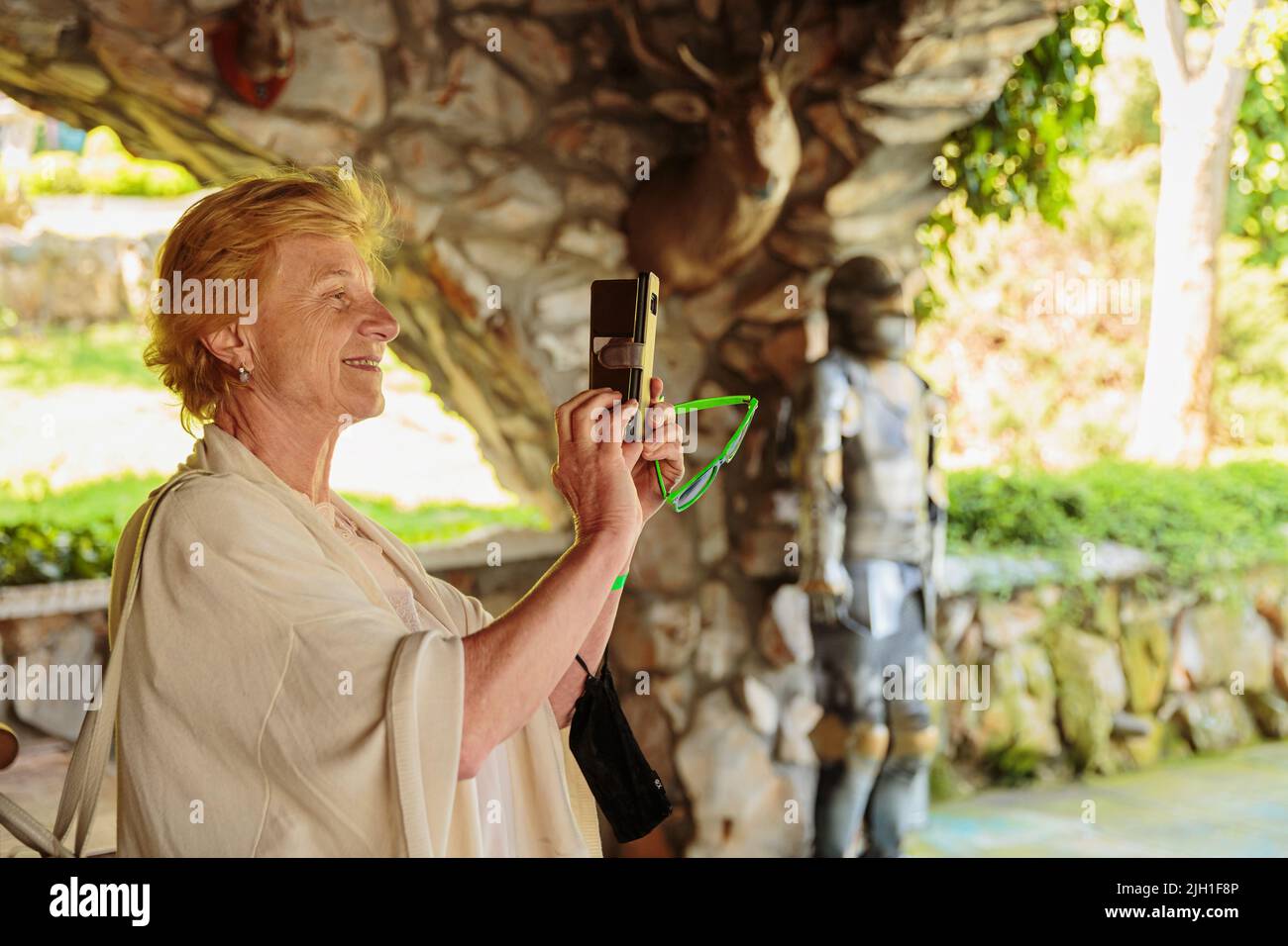 Ältere Frau, die in einem alten Schloss Fotos auf ihrem Telefon machte Stockfoto