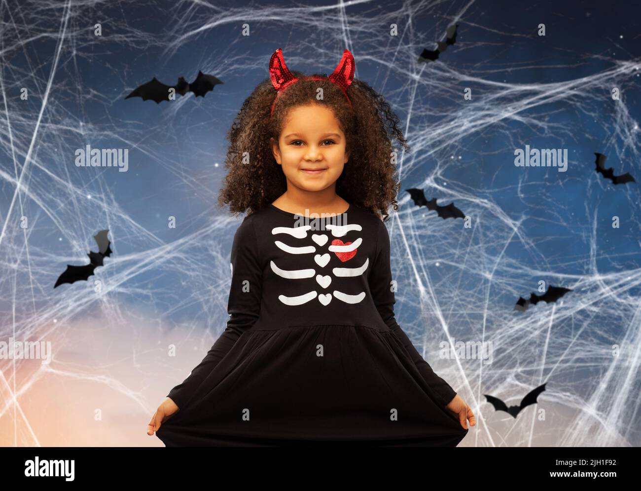 Mädchen in schwarzem Kleid und Teufelshörner an halloween Stockfoto