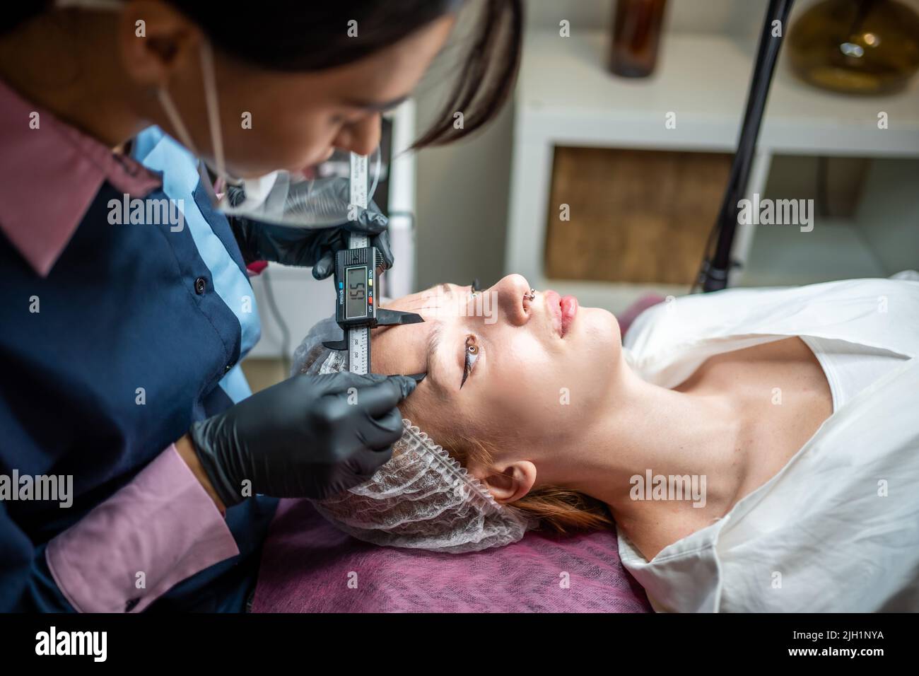 Beauty Master Messen Augenbrauen mit Zirkel vor permanentem Make-up. Stockfoto