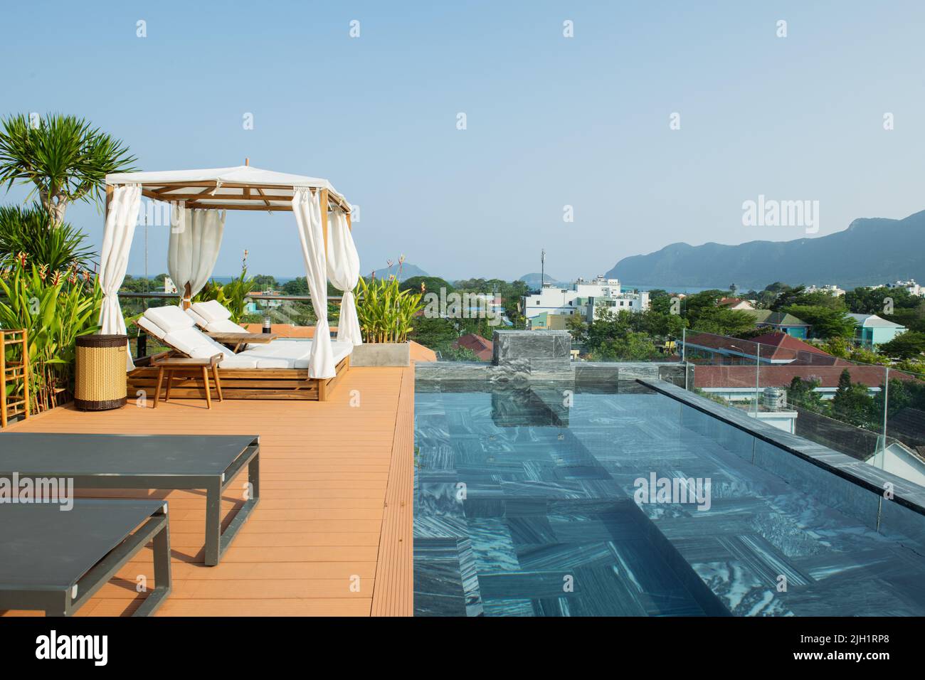 Liegestühle am Pool neben einem Überlaufpool, luxuriöser Überlaufpool am Morgen Stockfoto