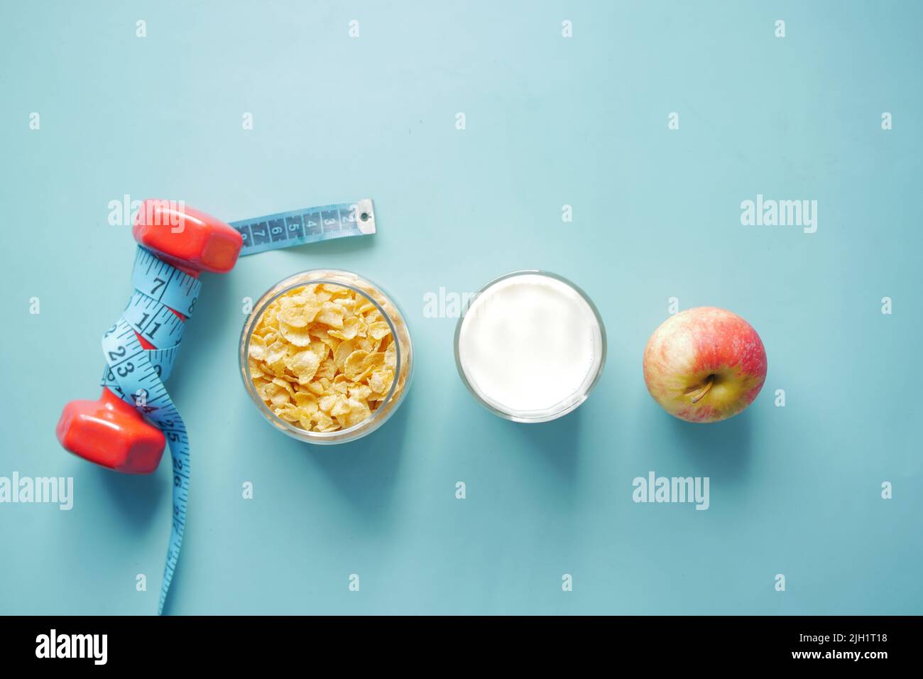Draufsicht auf Müsli, Apfel und Hantel auf blauem Hintergrund Stockfoto