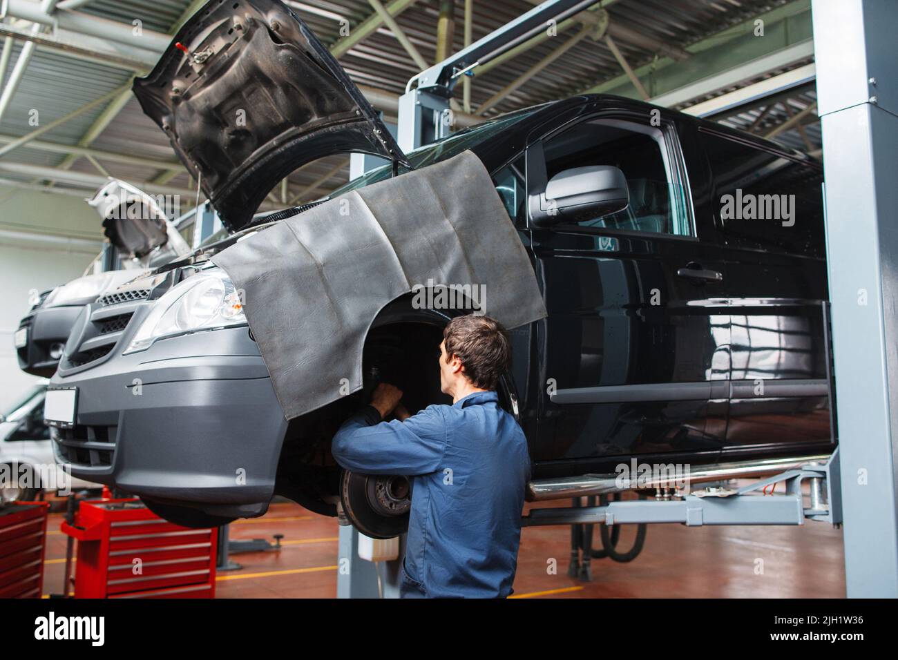 Wartemann, der die Bremsanlage im Auto in der Garage überprüft Stockfoto