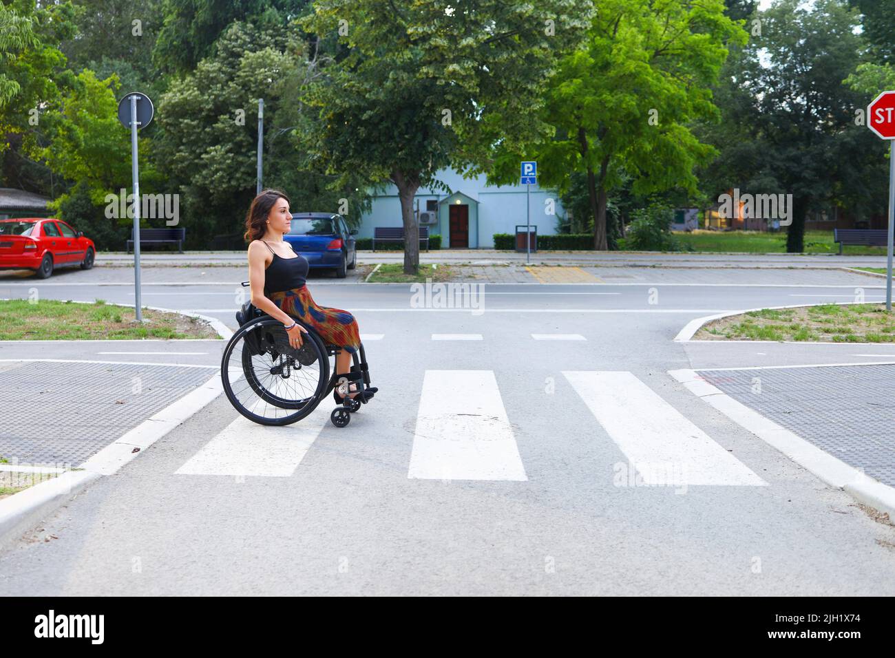 Eine Frau im Rollstuhl überquert sicher die Straße. Stockfoto