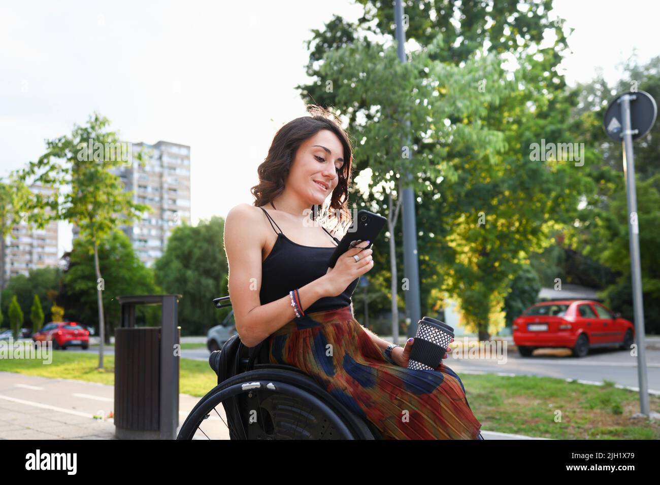 Junge Frau im Rollstuhl mit einem Smartphone Stockfoto
