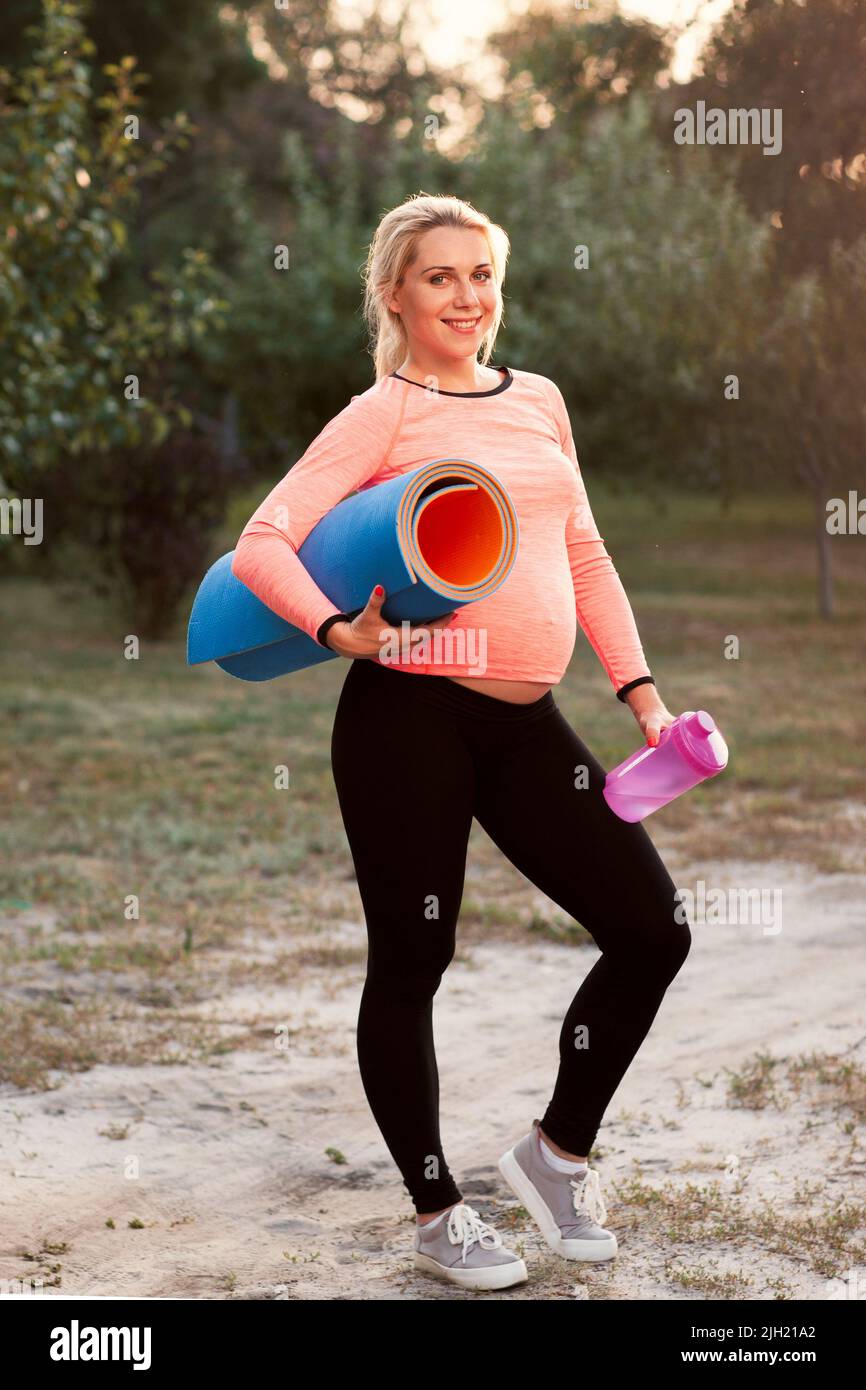 Lächelnde, schwanger Frau bereit für die Fitness im Freien Stockfoto
