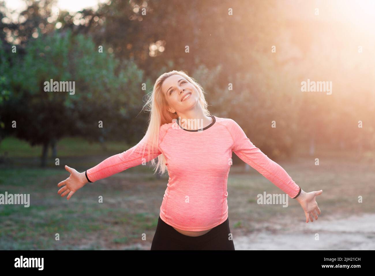 Glückliche, schwanger Frau, die den Moment, den Sonnenuntergang genießt Stockfoto