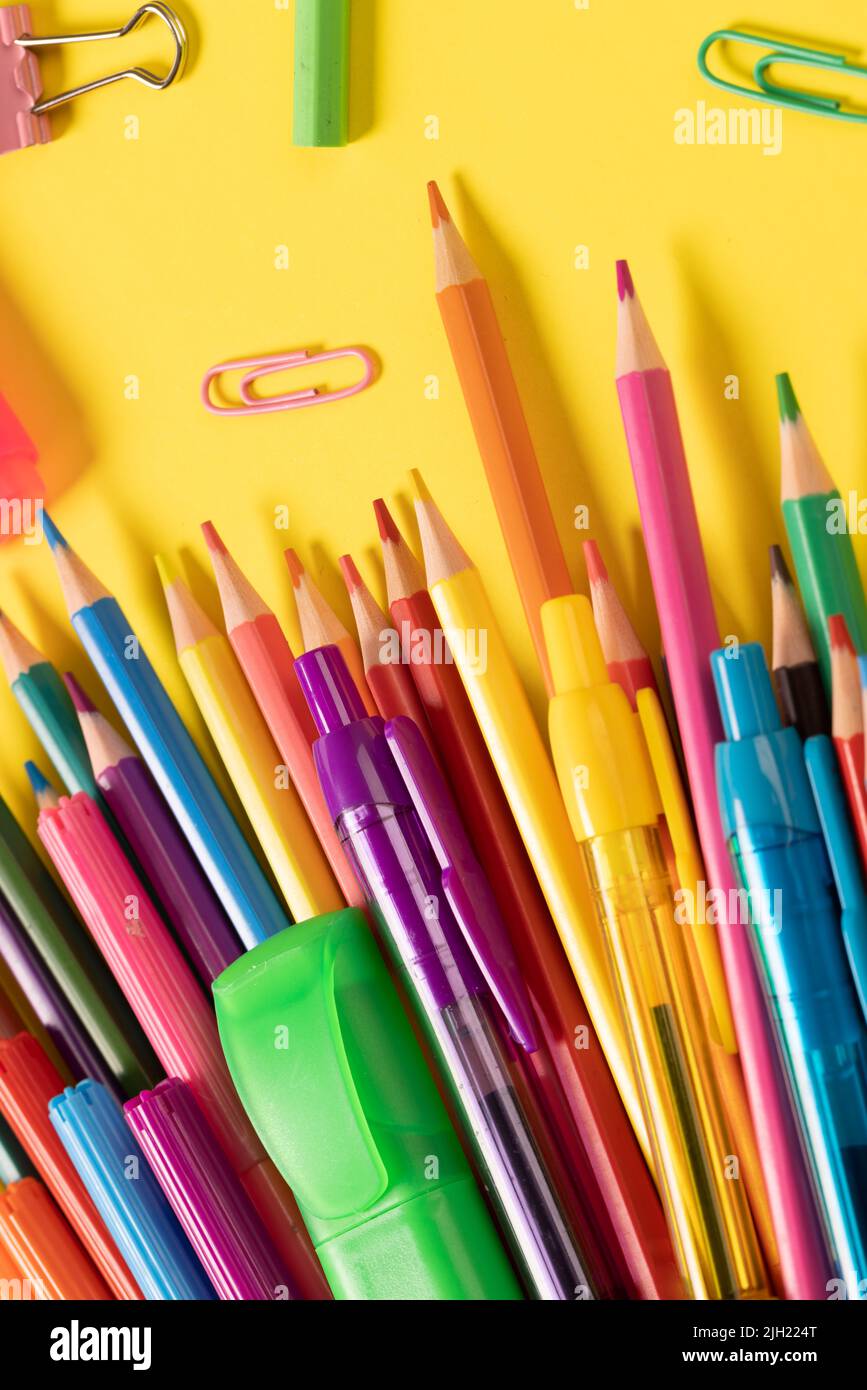 Stellen Sie sich verschiedene Büromaterialien und Plastikutensilien, Bleistifte, Buntstifte auf gelbem Hintergrund vor Stockfoto