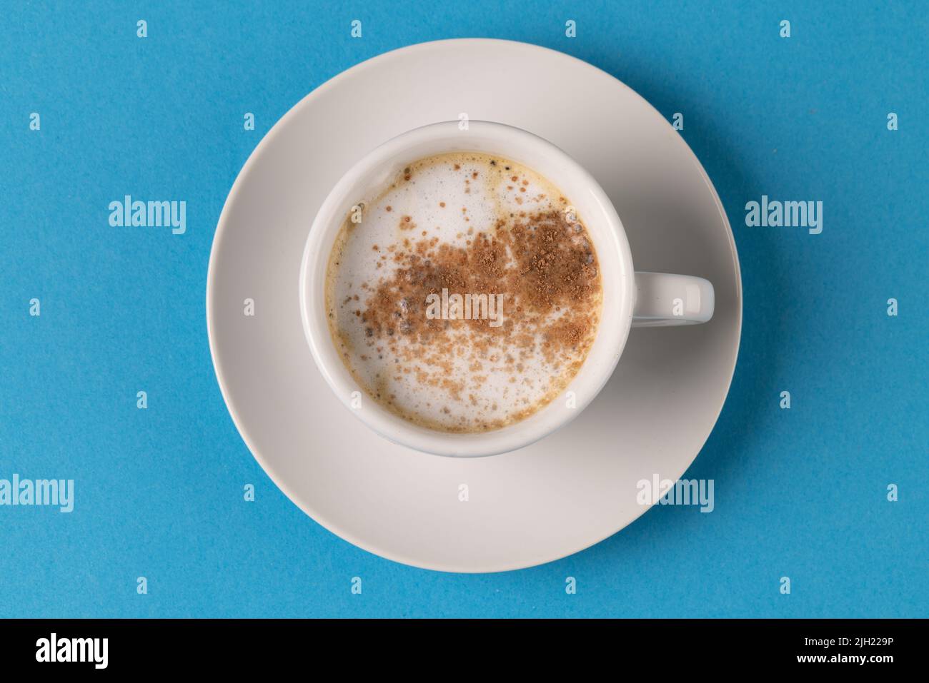 Bild einer weißen Tasse Kaffee mit Milch auf blauem Hintergrund Stockfoto
