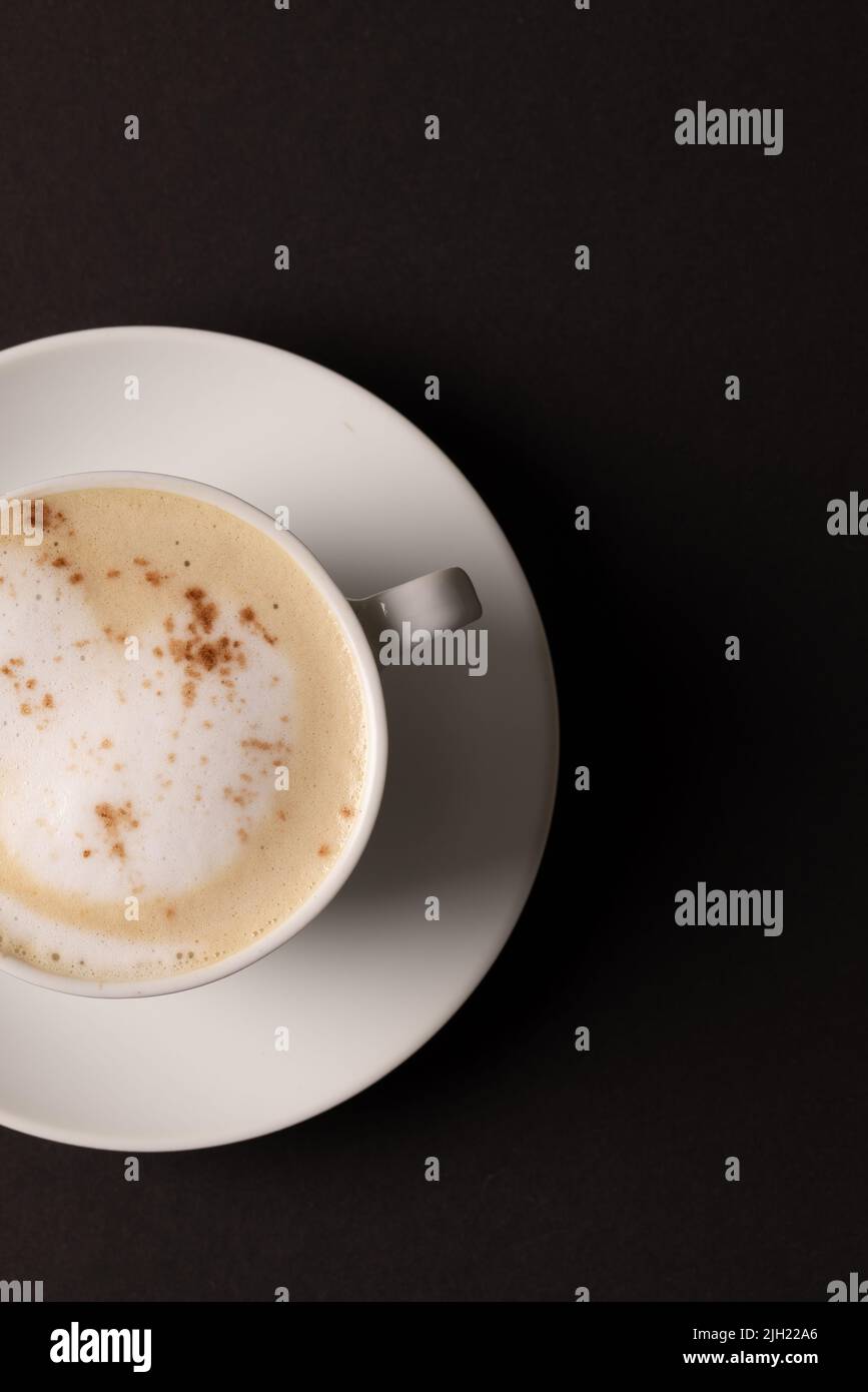 Bild einer weißen Tasse Kaffee mit Milch auf schwarzem Hintergrund Stockfoto