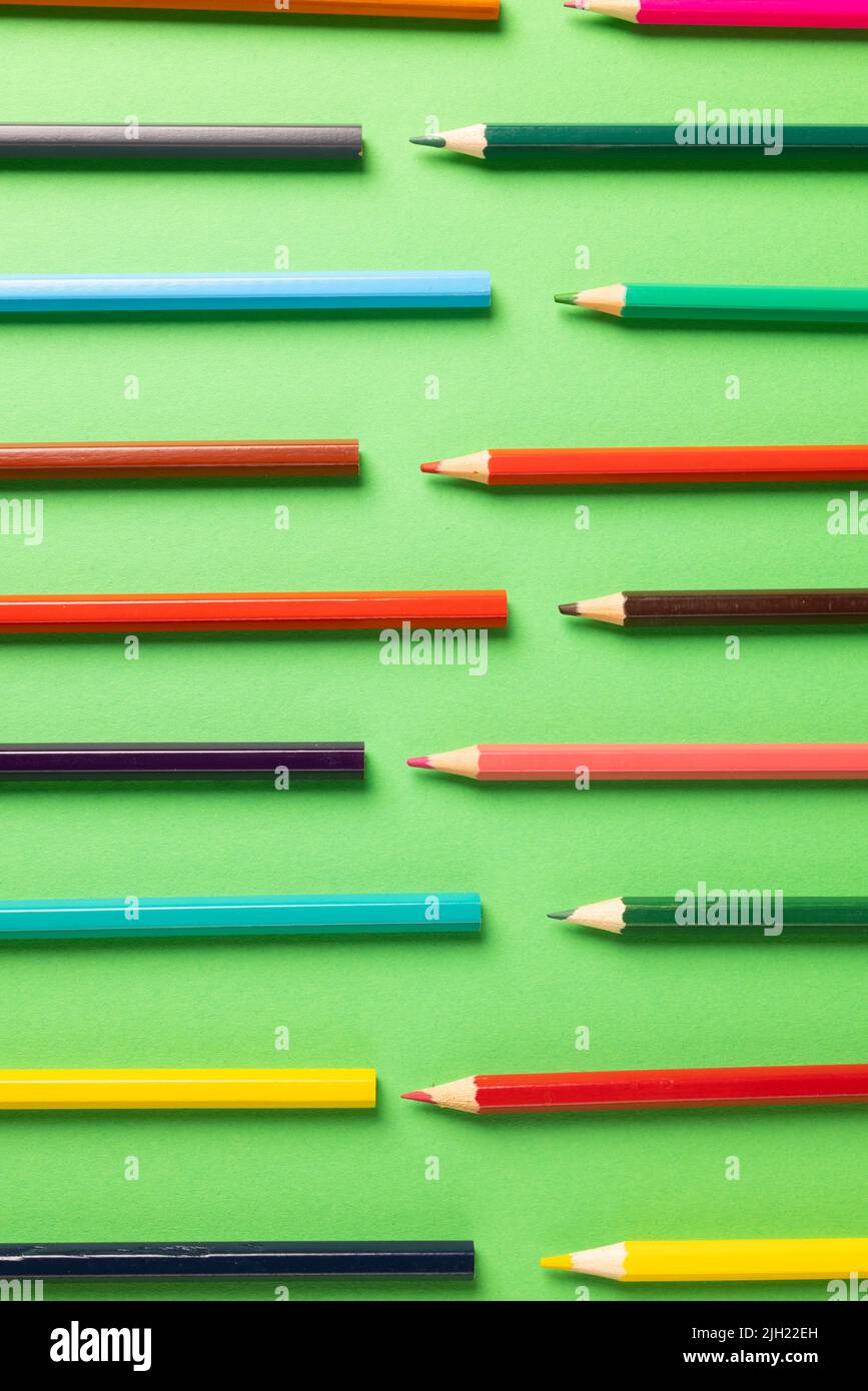 Vertikale Zusammensetzung von bunten Buntstiften auf grüner Oberfläche Stockfoto