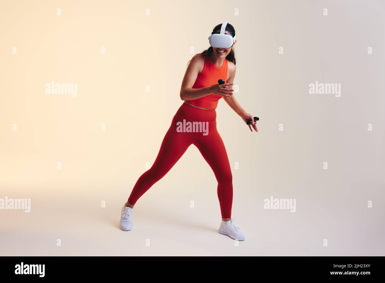 Junge Frau, die Spaß mit der 3D-Technologie hat. Glückliche junge Frau lächelt fröhlich, während sie ein Virtual-Reality-Spiel erkundet. Weibliche Gamer trägt eine virtuelle Stockfoto