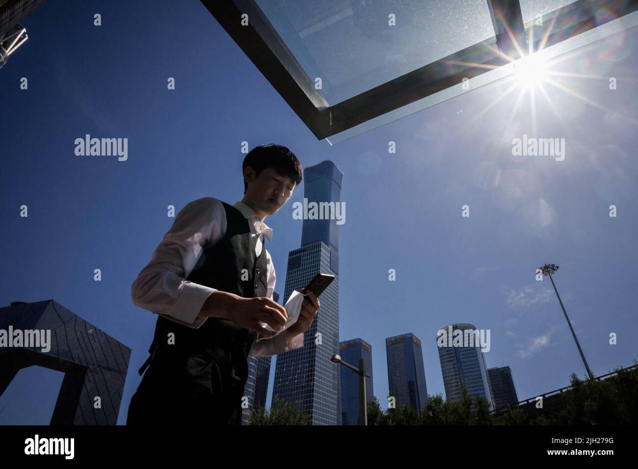 Ein Mann geht vor die Skyline des Central Business District in Peking, China, 14. Juli 2022. REUTERS/Thomas Peter Stockfoto