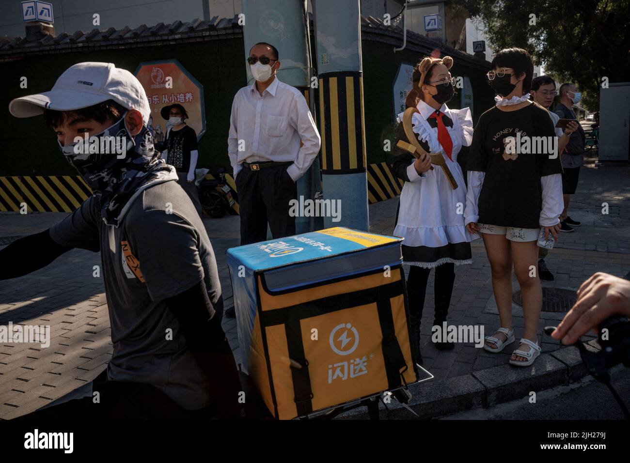 Ein Lieferfahrer wartet mit Menschen an einer Ampel in Peking, China, 14. Juli 2022. REUTERS/Thomas Peter Stockfoto