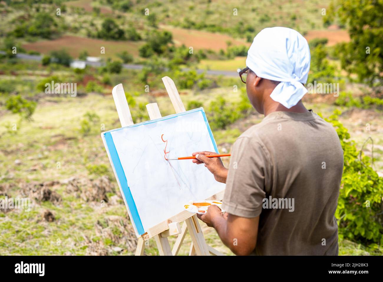 Künstler malen oder zeichnen auf Leinwand, indem sie Berge und die Natur auf dem Gipfel des Hügels sehen - Konzept von Hobbys, Freizeitaktivitäten, Kreativität. Stockfoto