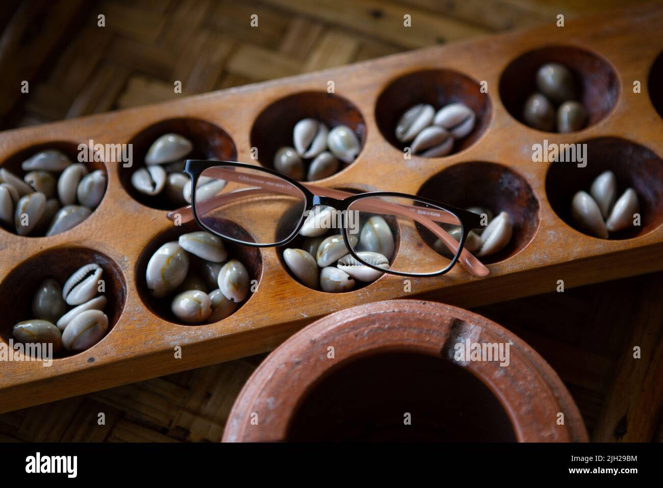 Congklak, ein traditionelles Spiel, das ein Holzbrett mit 14 bis 16 runden Löchern verwendet Stockfoto