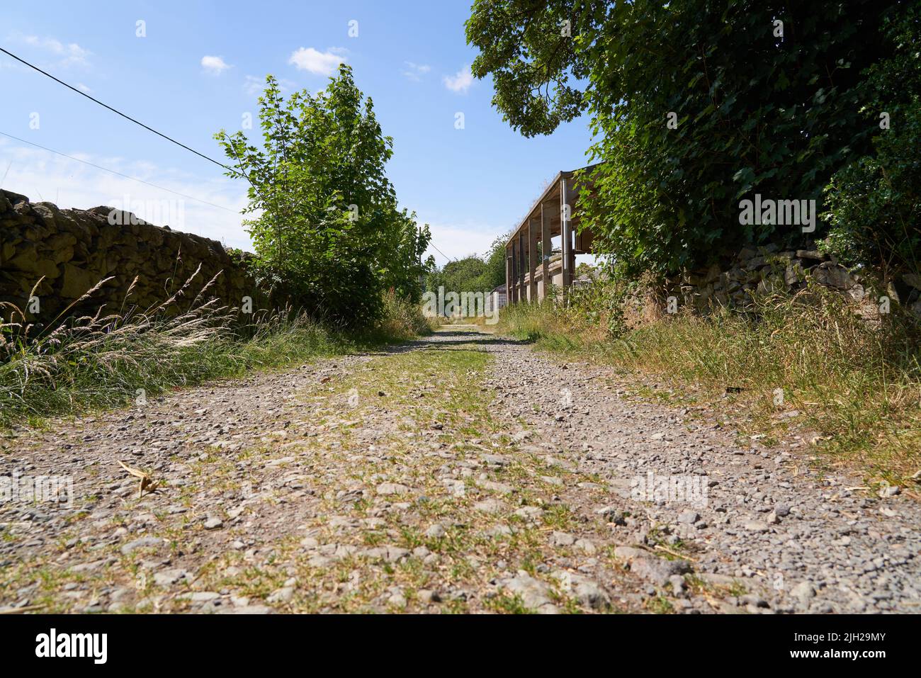 Lange, raue Farm-Strecke an einem sonnigen Tag Stockfoto