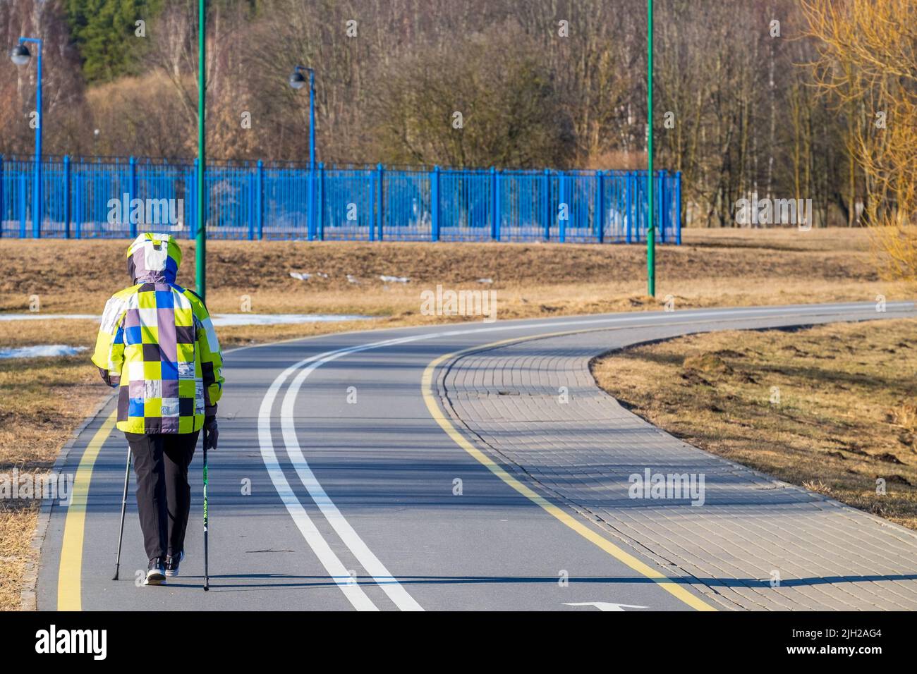 Minsk, Weißrussland - 9. März 2022: Nordic Walking. Eine Frau macht an einem sonnigen Tag Sport auf einer Sportstrecke im Park Stockfoto