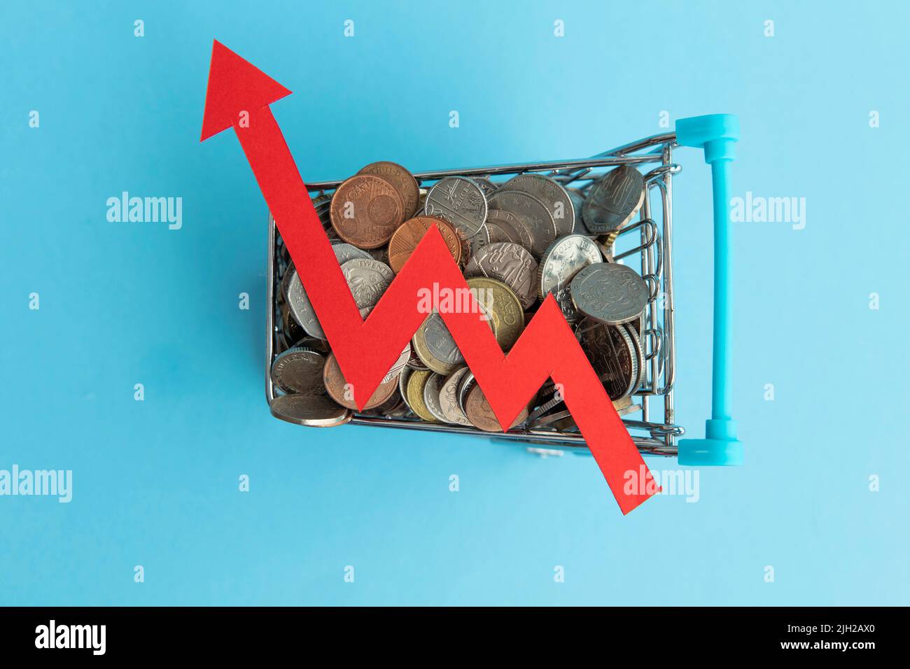 Einkaufswagen voller Münzen und einem roten Inflationspfeil Stockfoto