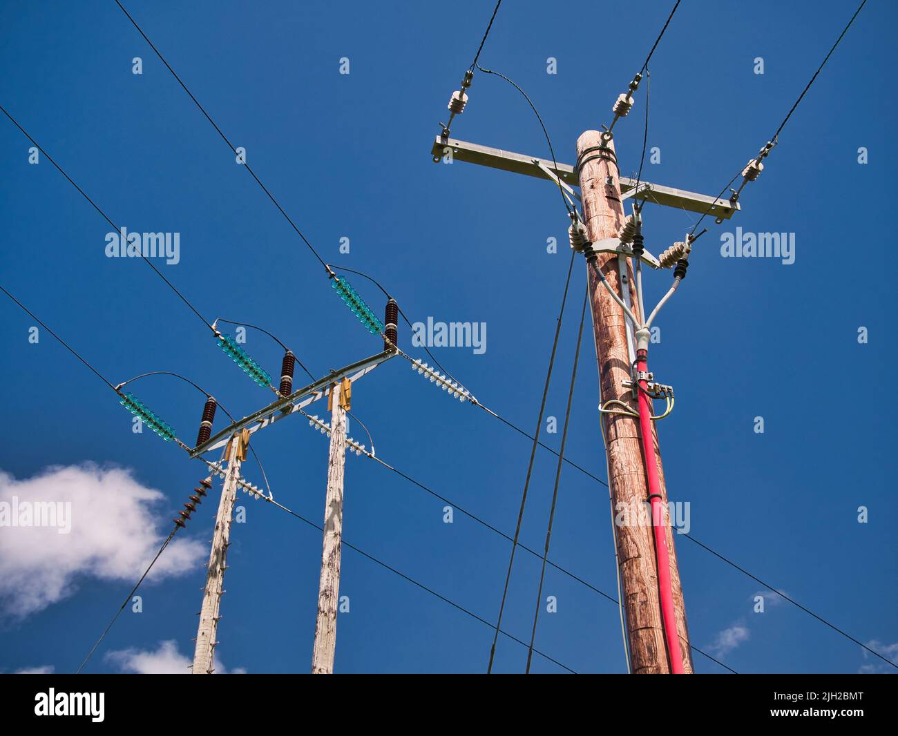 Zwei Strommasten, die Strom über das britische Stromnetz liefern, zeigen Stromkabel, Isolatoren und andere Geräte. An einem sonnigen Tag aufgenommen Stockfoto
