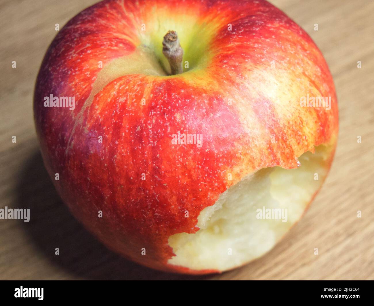 Großer Apfel auf einem hölzernen Hintergrund gebissen. Reifer roter Apfel. Stockfoto