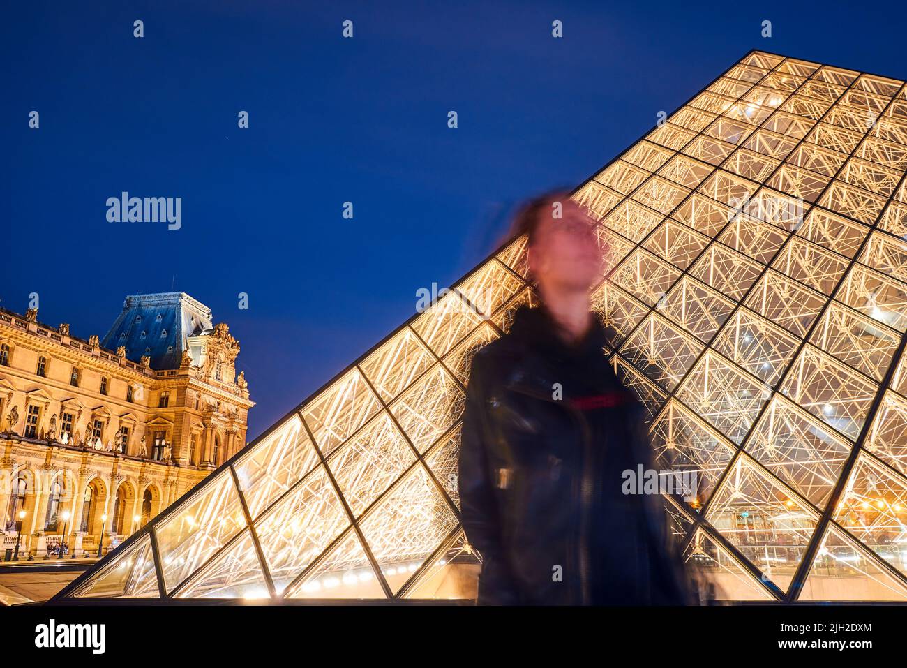 Silhouette eines Mädchens auf einem Hintergrund im Louvre in Paris bei Nacht Stockfoto