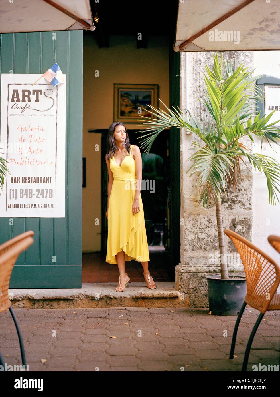 Eine Frau in Diane von Furstenberg-Kleid steht vor der Tür zu einem Café in Santo Domingo, Dominikanische Republik. Stockfoto