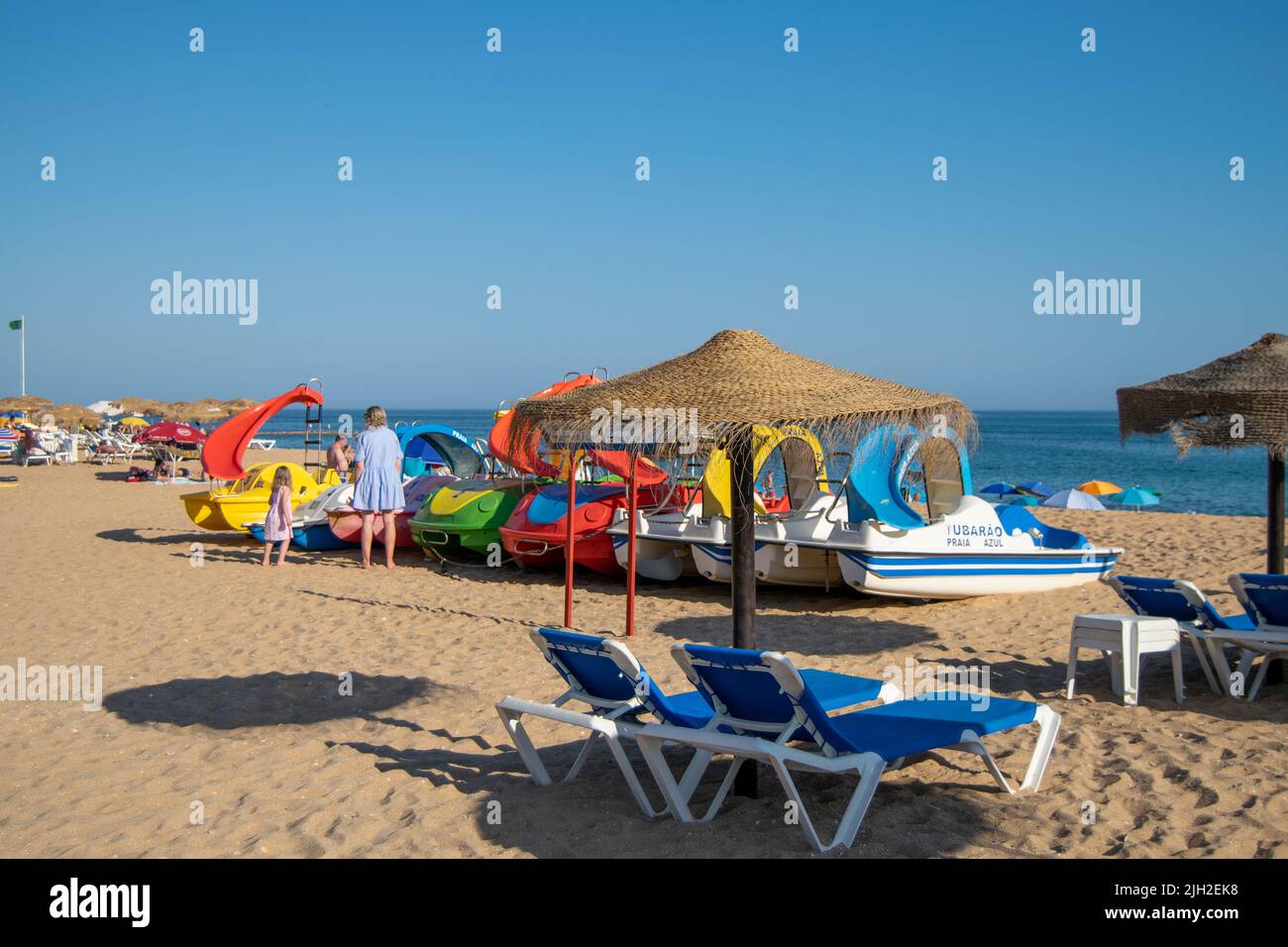 Sommerstrandtage, Strandgeschäfte, touristische Waren am Strand. Sonnenschirm und Mietboote. Urlaub und Ferien. Algarve Süd Portugal. Stockfoto