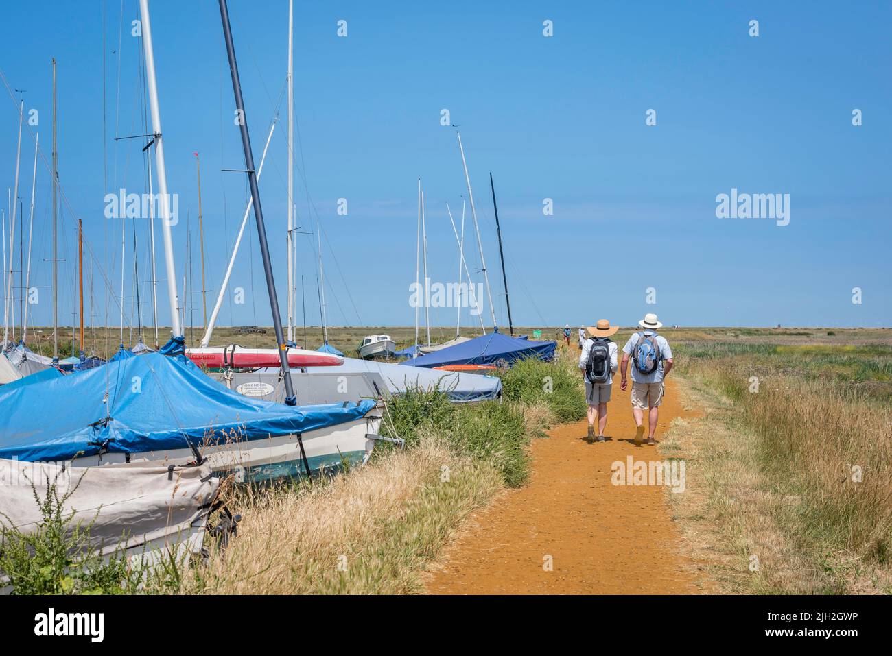 Paar wandern im Sommer, Rückansicht eines reifen Paares, das an einem heißen Sommertag auf dem North Norfolk Coast Path in der Nähe von Blakeney, Norfolk, England, Großbritannien, unterwegs ist Stockfoto
