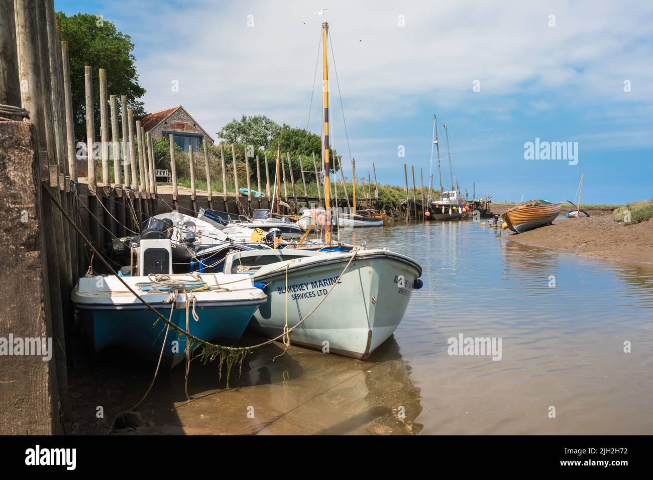 Blakeney Quay, Blick im Sommer auf Boote, die am Kai im nördlichen Norfolk-Dorf Blakeney, Norfolk, England, Großbritannien, festgemacht sind Stockfoto