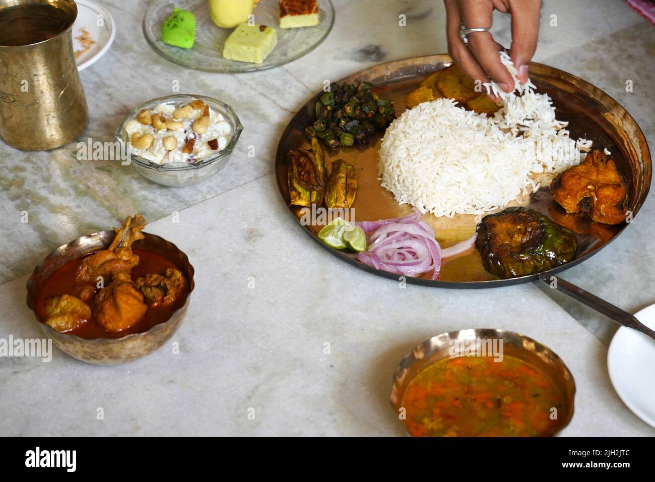 ESSEN VON BENGALISCHEM THALI IN KUPFERPLATTE MIT HÜHNERSALAT UND SÜSSEN BEILAGEN Stockfoto