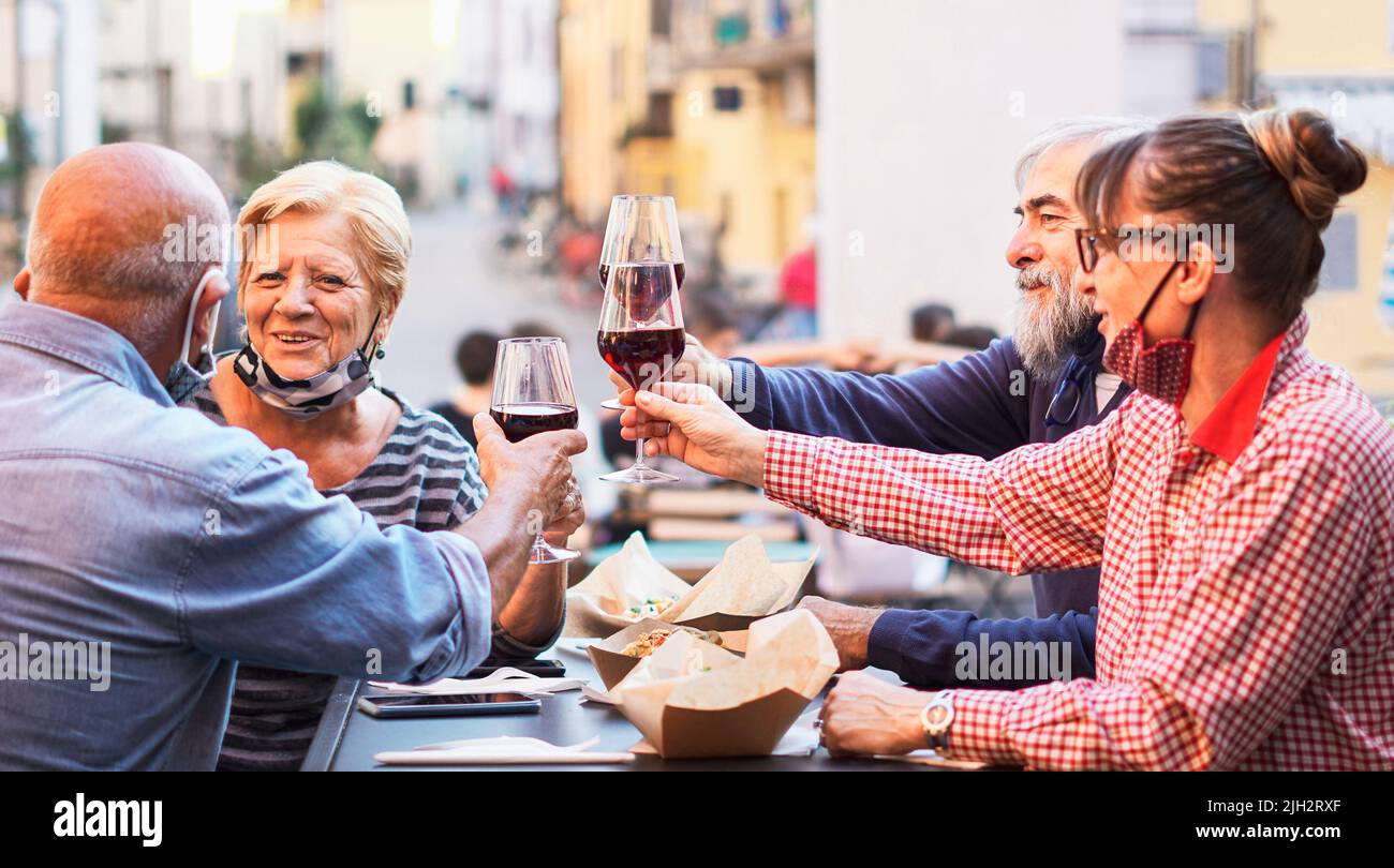 Gruppe alter Leute, die draußen essen und trinken - doppelt Datum mit Gesichtsmask auf - Fokusgläser Stockfoto
