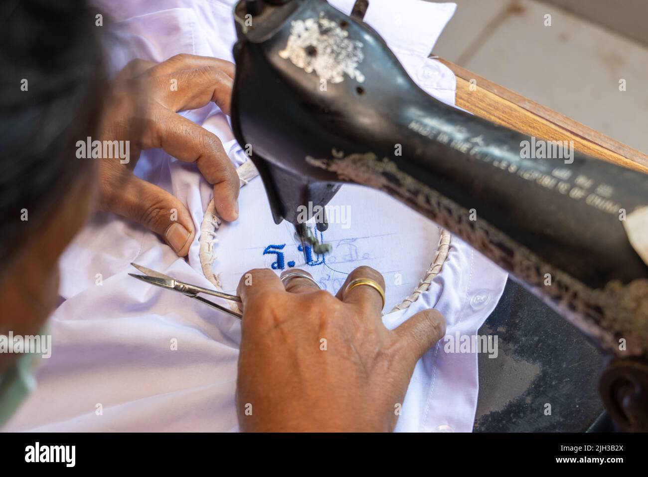 Sticken von Thai-Nummern auf einem Studentenhemd auf einer alten Nähmaschine Stockfoto